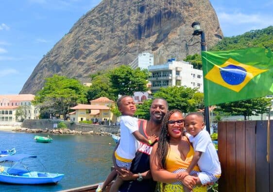 Mom and dad, with their twin 4 year old sons posing with the Brazilian flag and Sugarloaf Mountain in the backdrop