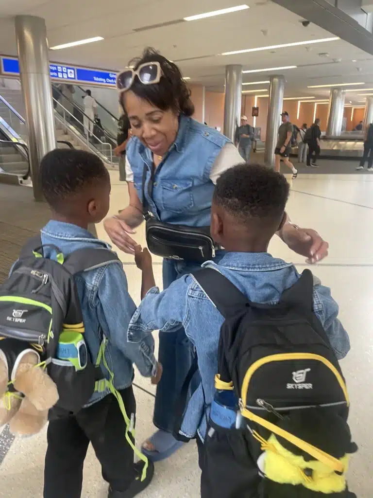 My twins greeting my mom at the airport with their travel backpacks in town