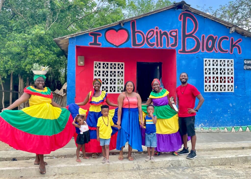 My family and I in front of a sign in Palenque, Colombia that says I love Being Black. I'm wearing a flowy maxi skirt—perfect for packing for Colombia.