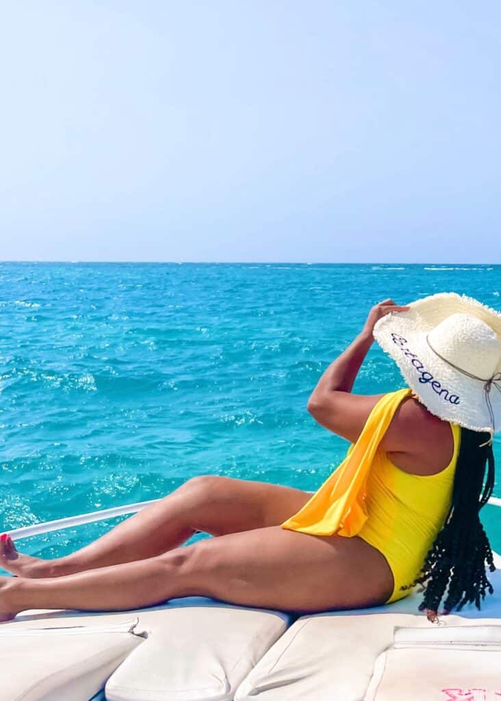 Me in my bright yellow one piece swimsuit and my straw hat on a boat in Cartagena.