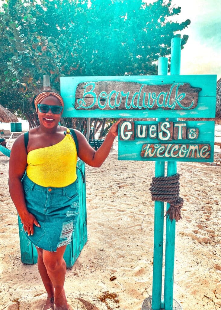 Me in front of the Boardwalk sign wearing a denim skirt and a yellow one-shoulder top. 