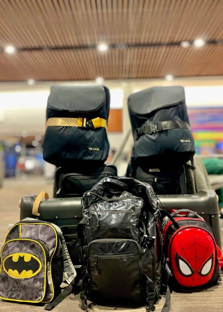 A pile of our family's carry-on only luggage at the airport—even the kiddos are minimalist travelers!