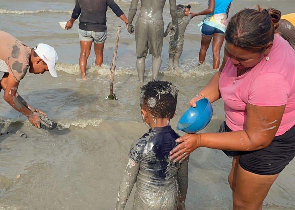 A local woman washing the mud off my son after we got out of Cartagena's mud volcano. 