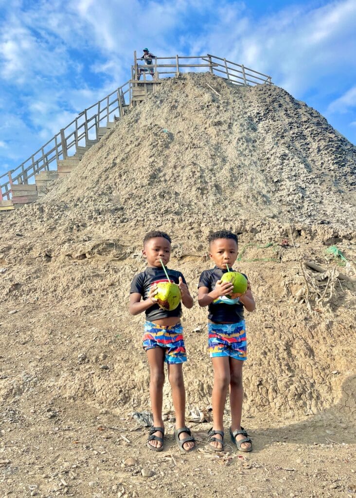 The twins sipping coconut water directly from the coconut before we got in the mud volcano.