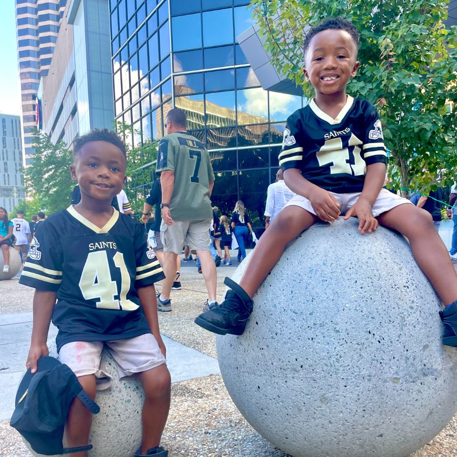 My twin boys sitting on decor outside of the Superdome after a saints football game