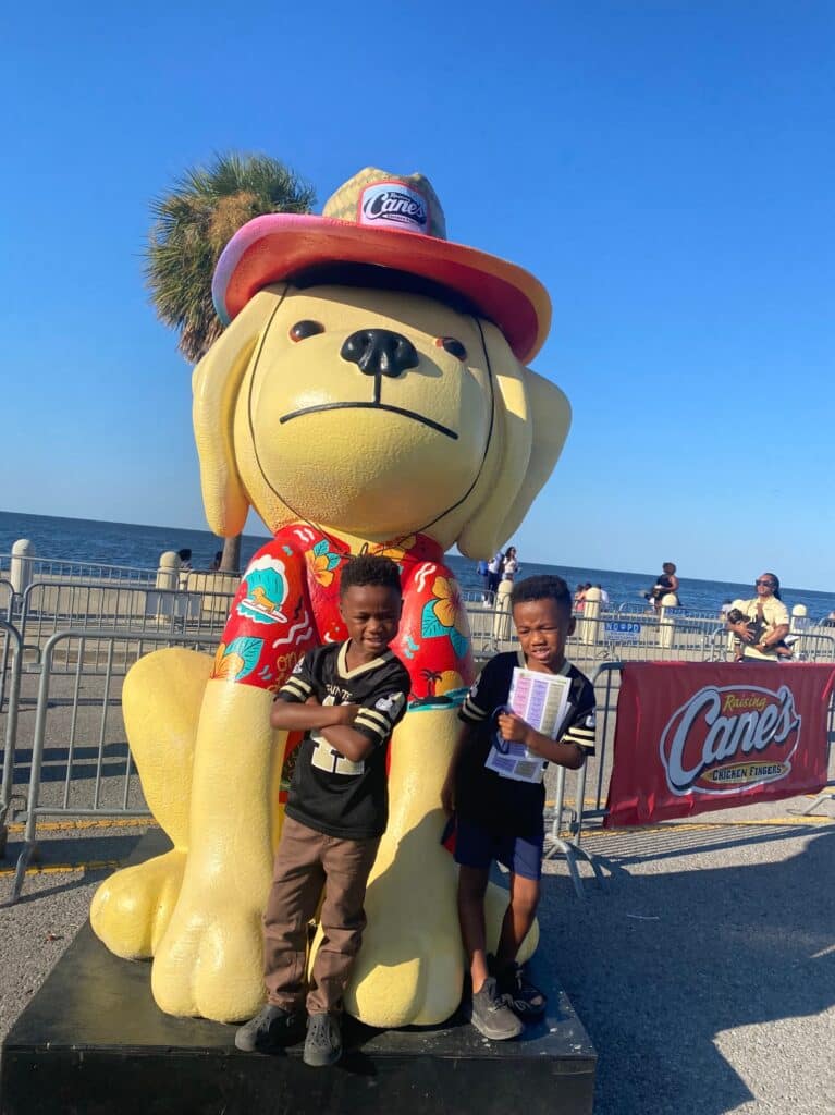 The boys in front of the Raising Cane's dog mascot at the Fried Chicken Festival.